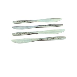 May include: Four silver dinner knives with a decorative pattern on the handle.
