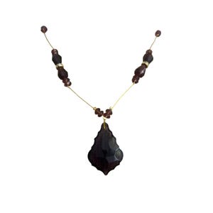 May include: A dark purple necklace with a large, faceted pendant. The necklace features small, round beads and larger, oblong beads in a matching color. The chain is a thin, gold-colored wire.
