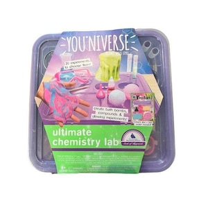 May include: A purple plastic container holds a science kit labeled "YOU*NIVERSE Ultimate Chemistry Lab." The kit includes a variety of experiments to create bath bombs, compounds, and glowing experiments. The kit includes a bonus poster. The packaging features a colorful design with text and images.