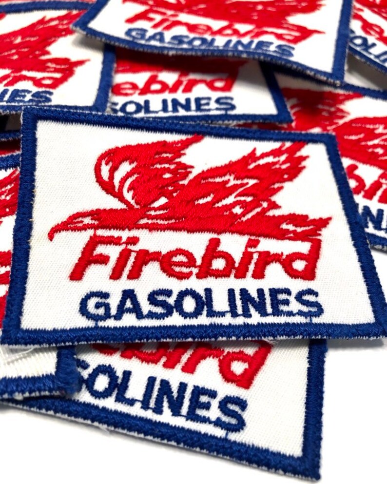 May include: A stack of white fabric patches with blue and red embroidery. The patches feature a red stylized bird with the text "Firebird Gasolines".