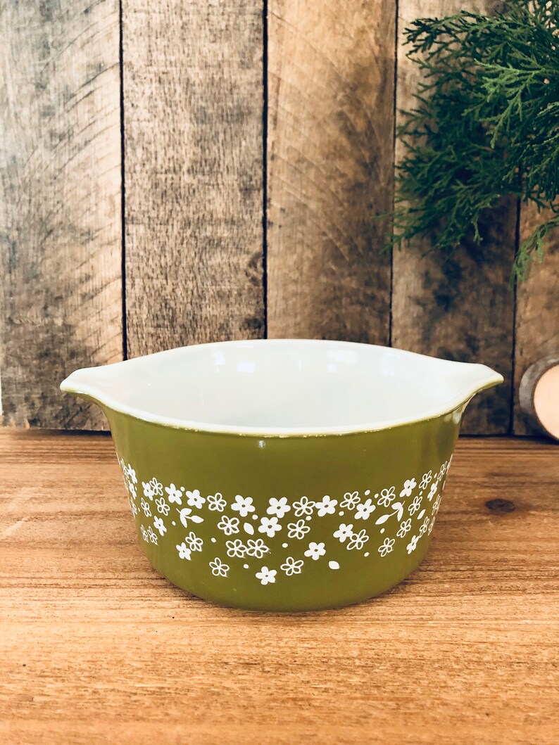 May include: A green ceramic baking dish with a white floral pattern. The dish has two handles on the sides.