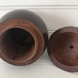 May include: A wooden box with a round lid. The box is dark brown and has a smooth finish. The lid is open and the inside of the box is visible.