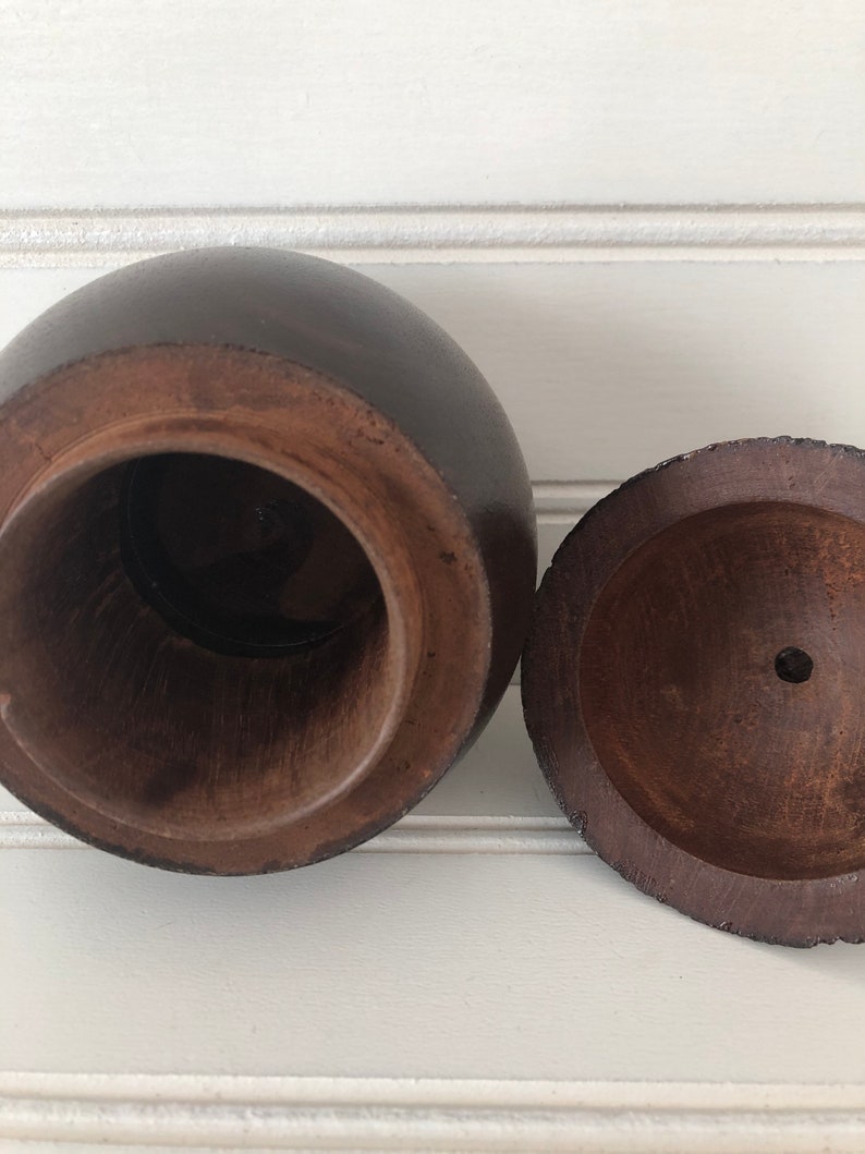 May include: A wooden box with a round lid. The box is dark brown and has a smooth finish. The lid is open and the inside of the box is visible.
