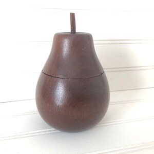 May include: A dark brown wooden pear-shaped box with a lid. The box is made of wood and has a smooth finish.