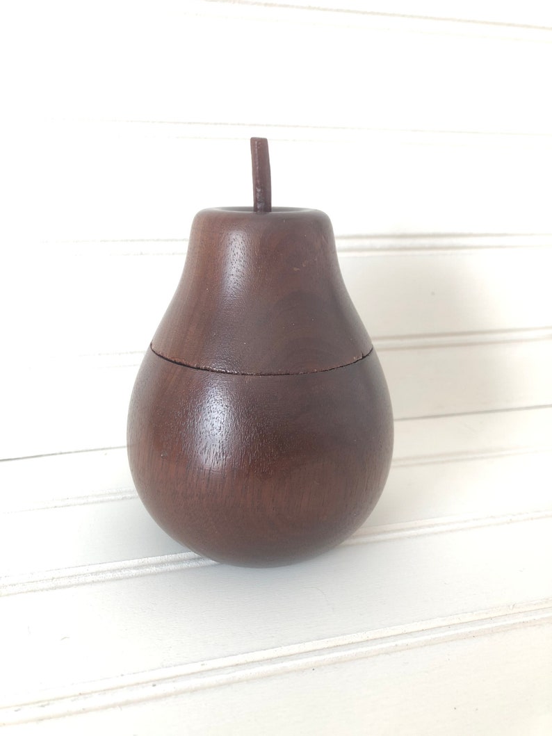 May include: A dark brown wooden pear-shaped box with a lid. The box is made of wood and has a smooth finish.
