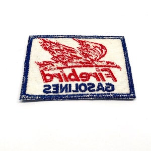 May include: A white fabric patch with blue stitching around the edges. The patch features a red embroidered bird with the text "GASOLINE FIREBIRD" in red and blue embroidery.