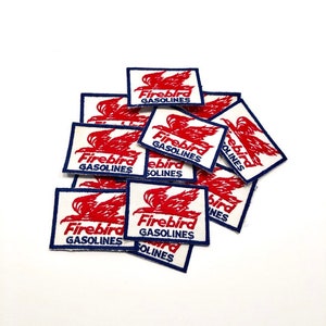 May include: A pile of vintage Firebird Gasolines patches. The patches are white with a red bird design and blue trim. The text "Firebird Gasolines" is printed in blue on each patch.