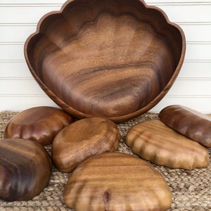 Pode incluir: Um conjunto de tigelas de madeira em forma de concha. As tigelas são feitas de madeira marrom escura e têm um acabamento liso e polido. O conjunto inclui uma tigela grande e várias tigelas menores.