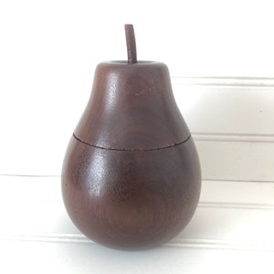 May include: A dark brown wooden pear-shaped box with a lid. The box is made of wood and has a smooth finish.