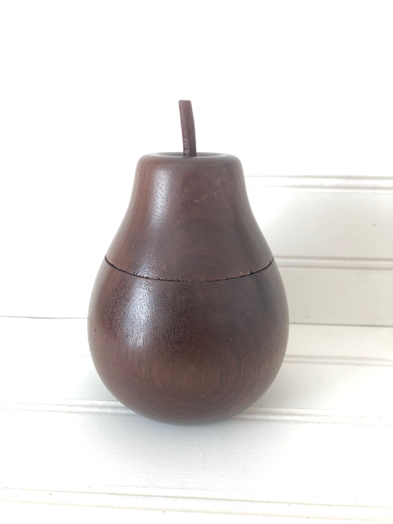 May include: A dark brown wooden pear-shaped box with a lid. The box is made of wood and has a smooth finish.