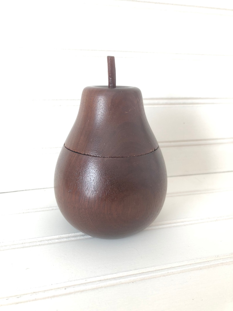 May include: A dark brown wooden pear-shaped box with a lid. The box is made of wood and has a smooth finish.