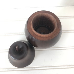 May include: A dark brown wooden box shaped like an apple with a lid that fits inside the top. The lid has a small knob on top.