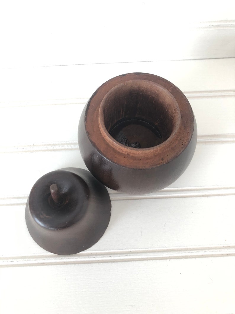 May include: A dark brown wooden box shaped like an apple with a lid that fits inside the top. The lid has a small knob on top.