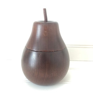 May include: A dark brown wooden pear-shaped box with a lid. The box is made of wood and has a smooth finish.
