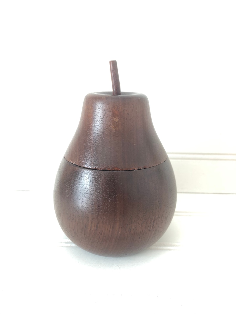 May include: A dark brown wooden pear-shaped box with a lid. The box is made of wood and has a smooth finish.
