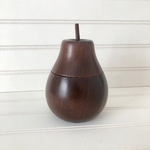 May include: A dark brown wooden pear-shaped box with a lid. The box is made of wood and has a smooth finish.