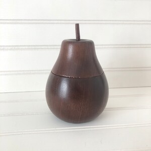 May include: A dark brown wooden pear-shaped box with a lid. The box is made of wood and has a smooth finish.