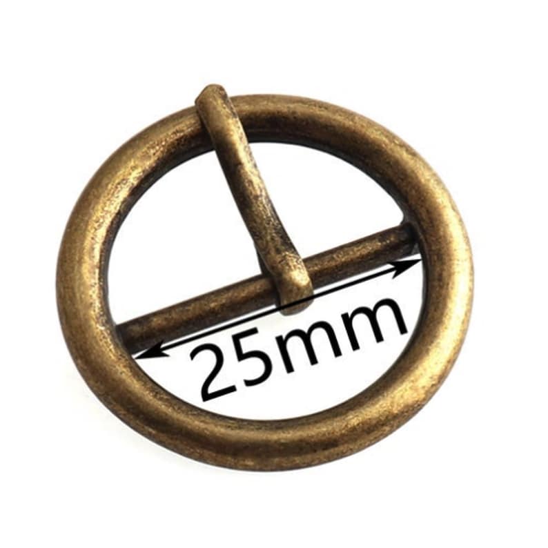 May include: A gold-toned metal buckle with a round shape and a 25mm diameter. The buckle is designed to be used with a belt or strap.