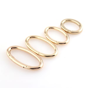 May include: Four gold-toned oval-shaped metal clasps of varying sizes.