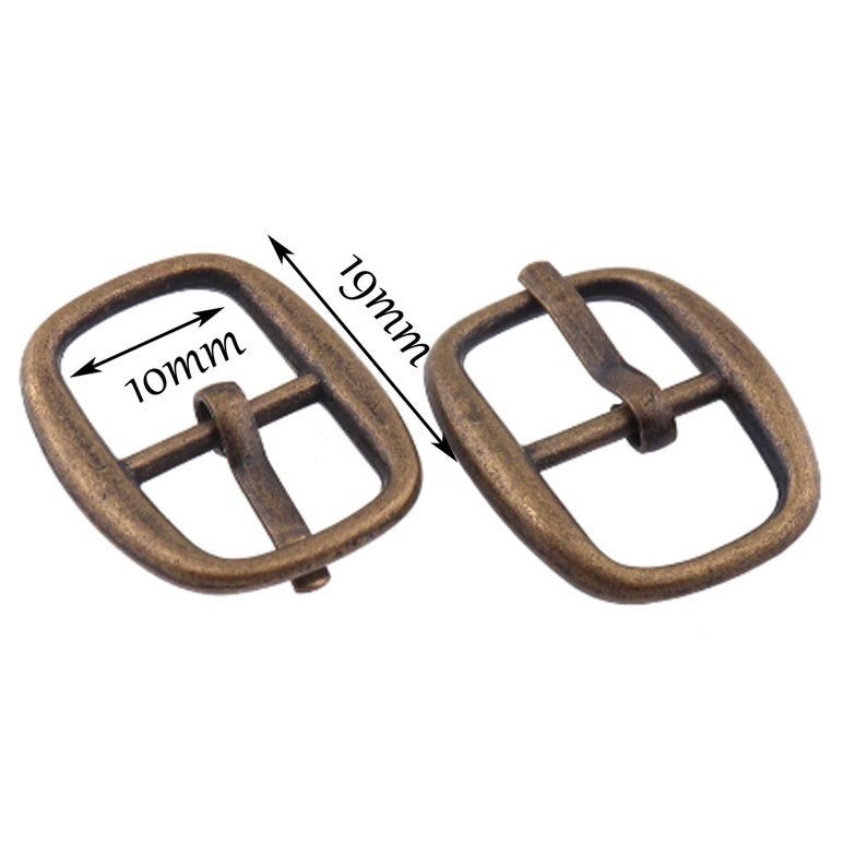 May include: Two antique gold-toned metal belt buckles. The buckle on the left measures 10mm wide and 19mm long. The buckle on the right is the same size.