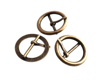 Puede incluir: Tres hebillas de cinturón de metal dorado antiguo. Cada hebilla es redonda con una barra central y un bucle para sujetar un cinturón.