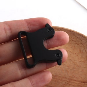 May include: Black metal buckle with a side release clasp. The buckle has two small holes on each side.