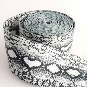 May include: A roll of white and black elastic webbing with a snake skin pattern.