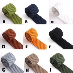 Puede incluir: Diez colores diferentes de cinta de algodón, cada uno enrollado y mostrando la textura acanalada. Los colores son verde, azul marino, blanco, marrón, naranja, negro, gris, beige y verde militar.