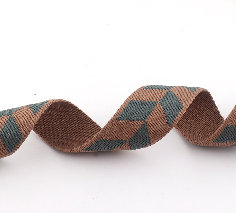 May include: Brown and green woven ribbon with a geometric pattern. The ribbon is twisted and curled.