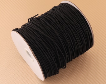 Peut inclure: Une bobine de cordon élastique noir, enroulée autour d'un noyau en carton blanc.