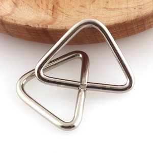May include: Two silver triangle-shaped metal rings, interlocked together.