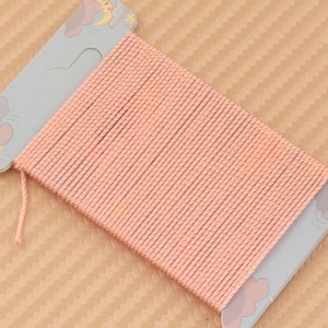 Può includere: Un rotolo di cordoncino color pesca con un simpatico disegno di cartone animato sulla confezione.