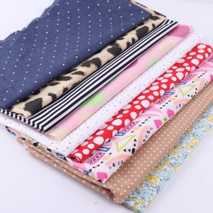 Könnte beinhalten: Ein Stapel aus acht verschiedenen gemusterten Stoffen. Die Stoffe haben Punkte, Streifen, Leopardenmuster und geometrische Muster in verschiedenen Farben, darunter Blau, Rot, Rosa, Weiß und Braun.