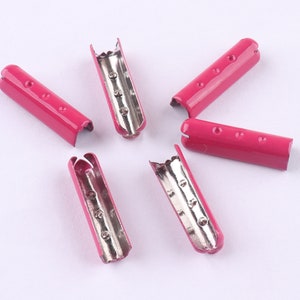 May include: Six pink metal cord ends with silver interiors. The cord ends are designed to be used for securing shoelaces, straps, or other cords.