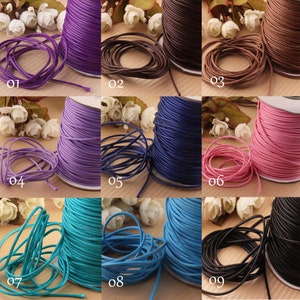 Op de afbeelding: Negen spoelen met gewaxt katoenen koord in verschillende kleuren, waaronder paars, bruin, roze, blauw, turquoise en zwart. Elke spoel is genummerd van 01 tot 09.