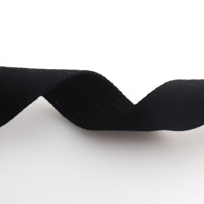 K&ouml;nnte beinhalten: Schwarzes Baumwollband, eine Art flaches, gewebtes Gewebe, ist in einer gekr&uuml;mmten Form dargestellt.