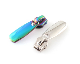 May include: Two zipper pulls, one is silver and the other is iridescent rainbow.