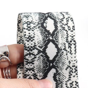 May include: Close-up of a white and black fabric with a snake skin pattern.