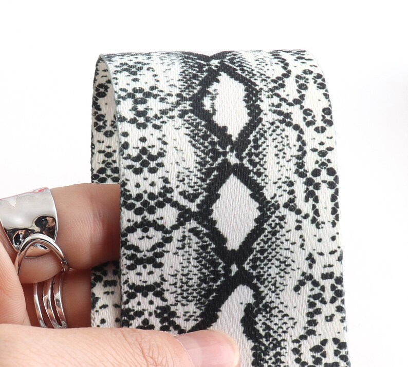 May include: Close-up of a white and black fabric with a snake skin pattern.