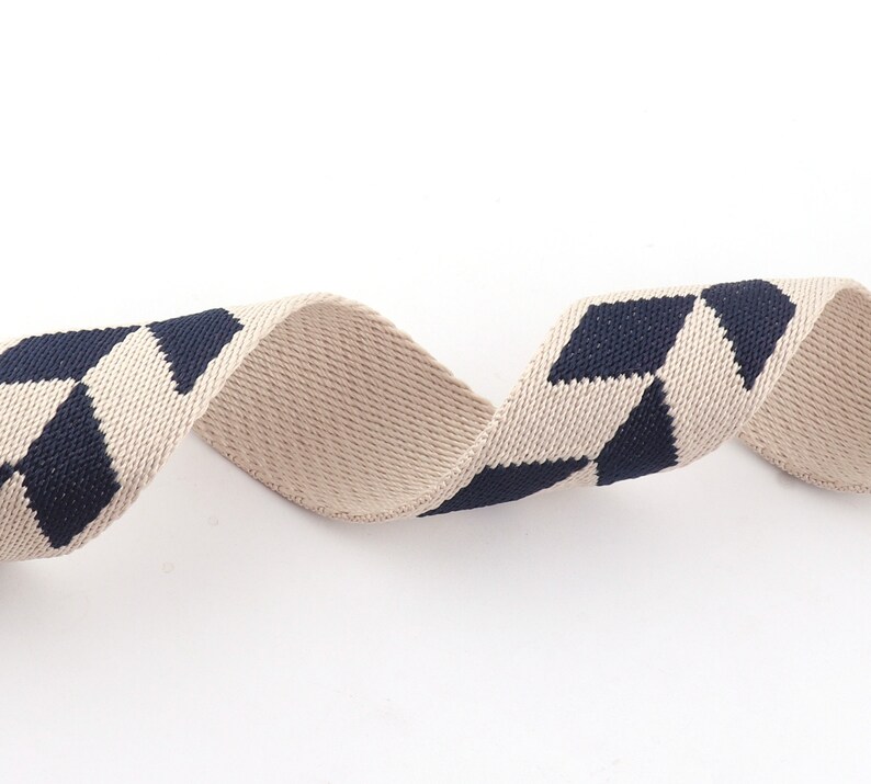 May include: Beige and navy blue woven ribbon with a diamond pattern.