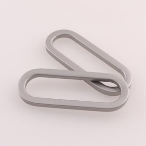 May include: Two silver oval-shaped metal rings, one on top of the other.