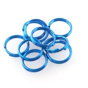 Puede incluir: Un grupo de anillos de salto de metal azul, utilizados para la fabricación de joyas y manualidades.