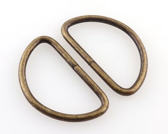 May include: Two antique gold-toned metal D-rings, each with a half-circle shape, connected together.