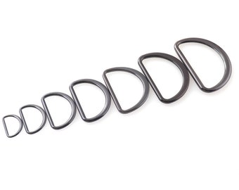 May include: A set of eight black metal D-rings of varying sizes. The rings are arranged in order of size, with the smallest ring on the left and the largest ring on the right.