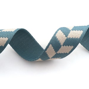 May include: A teal blue and white patterned ribbon with a geometric design. The ribbon is woven and has a soft texture.