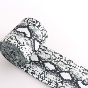 May include: A white and black elastic band with a snake skin pattern.