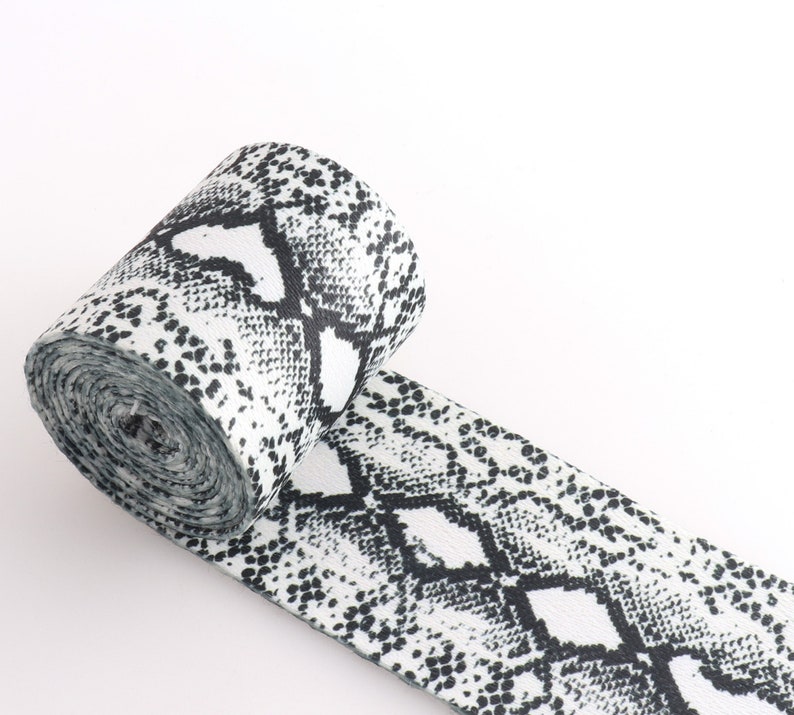 May include: A white and black elastic band with a snake skin pattern.