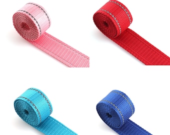 May include: Four rolls of reflective webbing in pink, red, blue, and turquoise. Each roll has a silver reflective stripe.