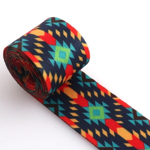 May include: A roll of colorful patterned webbing with a geometric design in shades of red, orange, yellow, blue, green, and black. The webbing is rolled up and the end is unfurled, showing the pattern.