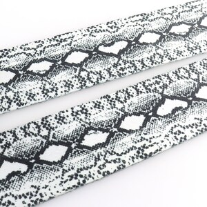 May include: White fabric with a black snake skin pattern.
